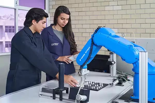 Estudiantes de la carrera de Ingeniería practicando con el brazo robótico en clase