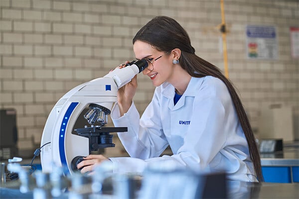 Alumna de la carrera de química farmacéutica de UNITEC utilizando un microscopio